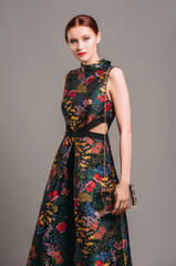 Cut out waist midi dress in floral embroidery with black high heels. Ginger lady walking in studio...