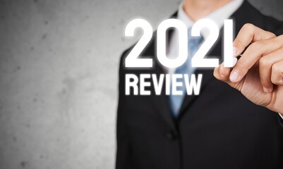 businessman writes 2021 review words results on virtual screen. economic indicators