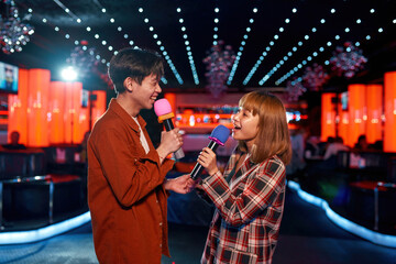 Asian couple in love singing song at karaoke party