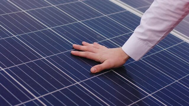 Closeup details at solar panels farm young hand checking the operation of sun and cleanliness of photovoltaic solar panels concept of ecological innovation