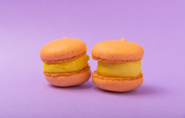 Delicious berry macaroons on a lilac paper background. French meringue cookies macaron. Culinary and cooking concept. Copy space.