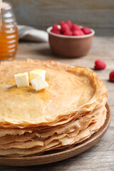 Stack of delicious crepes with melting butter on wooden table, closeup