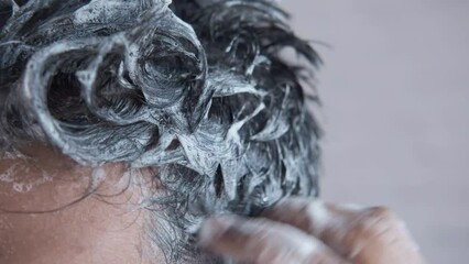 young men washes h his hair with shampoo .