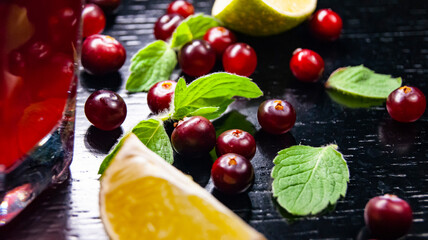 Glass with juice, lime wedge, mint and cranberries