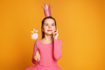 Cute girl in pink crown with magic wand on yellow background, space for text. Little princess
