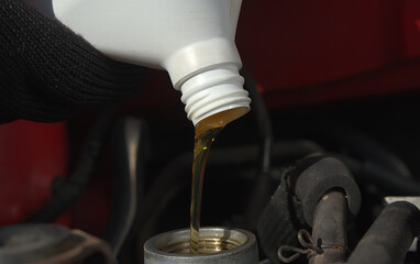 New transparent yellow engine oil is poured into a car engine