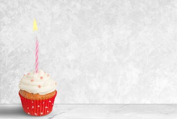 Birthday cupcake with a pastel-colored candle on a desk