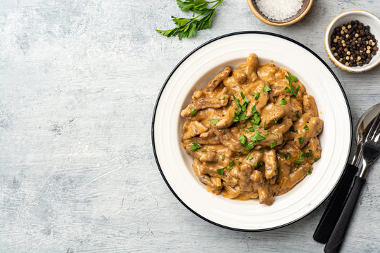 Traditional Russian dish Beef stroganoff in plate on concrete background