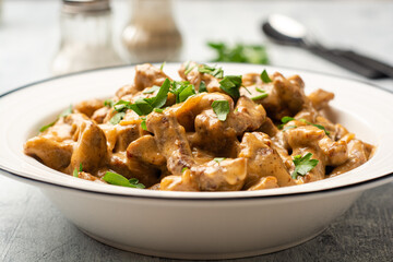 Traditional Russian dish Beef stroganoff in plate on concrete background