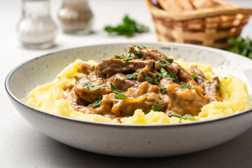 Traditional Russian dish Beef stroganoff with mashed potatoes in plate on concrete background