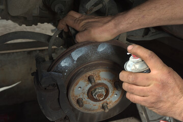 Brake disc treatment with a lubricant cleaning spray to check the brake system of a car