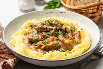 Traditional Russian dish Beef stroganoff with mashed potatoes in plate on concrete background