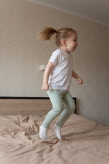 little girl jumping cheerfully on the bed