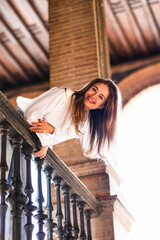 Lovely smiling Caucasian woman leaning on the railing of a balcony in the Plaza de España in Seville