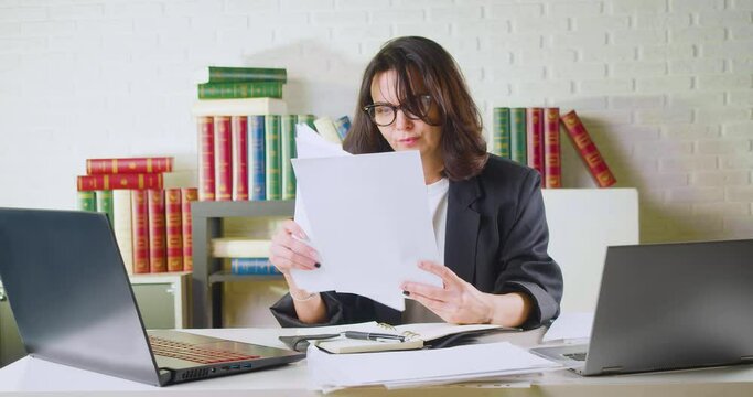 40-year-old business woman checks reports or tax forms, finds total errors and throws these documents away.