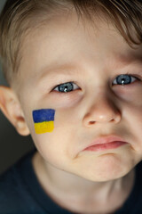 War in ukraine, a child with the flag of ukraine on his face. Pray for peace in Ukraine  mourning. No war.