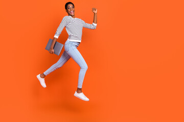 Photo of funny hurrying butch lady dressed sweater jumping holding gadget empty space isolated orange color background