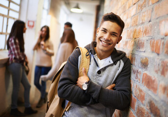 Friends make college fun. Portrait of a handsome young male student leaning against a wall with his...