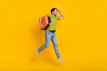 Full length profile side photo of young guy hold bag look empty space fly isolated over yellow color background