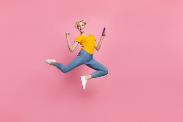 Fototapeta na wymiar Full size photo of pretty blonde hair casual wear female jumping raise fists in triumph isolated on pink color background