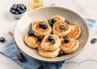 Cottage cheese fritters with blueberries on concrete background with copy space