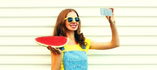 Summer portrait of happy smiling young woman taking selfie on smartphone with slice of watermelon on white background
