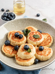 Cottage cheese fritters with blueberries on concrete background with copy space