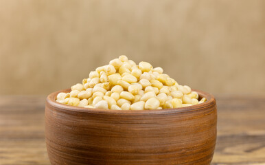 A bowl with pine nuts on a wooden background, delicious, natural. Soft focus.