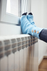 Woman's feet with woolen socks, enjoying inside home on the radiator.