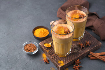 Healthy milk drink with turmeric, coffee and cinnamon on a dark background.