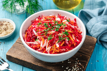 Beetroot salad with cabbage, carrots and sesame seeds on a blue background in a white sachet.
