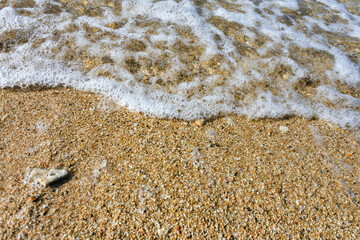 foam created by water waves and white sand on the beach