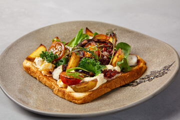 Bruschetta with octopus, vegetables and sauce on gray ceramic plate. Toast with octopus in contemporary style. Chef concept bruschetta in modern ceramic dishware. Handmade dinner plate.