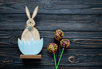 Easter bunny and candy on a stick on a black wooden background