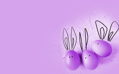 easter colored eggs with bunny ears on purple background.