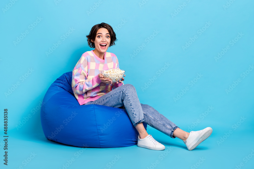 Sticker Full size profile side photo of young girl sit beanbag eat pop corn watch film isolated over blue color background