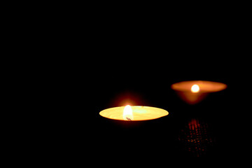 Round candles. floating candles in an aluminum column. Two lighted candles glow on a dark background.Low-light atmosphere.