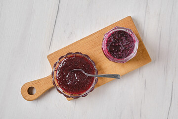 Overhead view of homemade blueberry jam in a jar and saucer