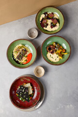 Set of meals on handmade ceramic dishware. Compositions from Chefs food on gray stone background in minimalistic style. Contemporary food - innovative recipes