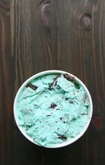 Top View of a Large Cup pf Mint Chocolate Chip Ice Cream on Dark Brown Wooden Backdrop