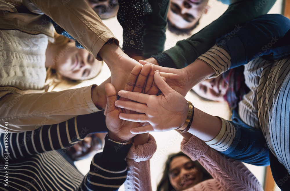 Poster theres power in unity. low angle portrait of a group of young friends standing with their hands in a