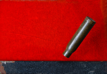 Cartridge case on a red background. Symbol of war and blood. Copy space. 