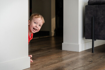 Child, toddler, little boy playing hide and seek at home. Joy at home, cozy heated floor. Creative...