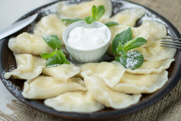 Vareniki with cottage cheese and sour cream, top view, selective focus