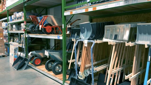 Hardware store departments and shelves with rows of shovels and hand carts (hand trolleys) for gardening or construction