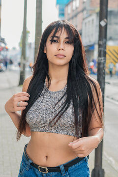 beautiful latina woman with brown skin standing on the sidewalk posing for photo shoot in the streets of Pereira-Colombia. fashion and beauty concept. university girl on the street.