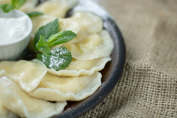 Vareniki with cottage cheese and sour cream, top view, selective focus