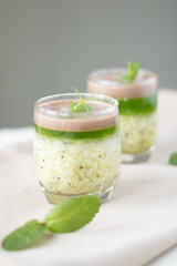 kiwi jelly and mint served on beige table, closeup. Panna cotta with kiwi jelly in a vintage jar on a light slate, stone or concrete background, traditional italian dessert.
