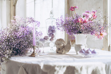 table set in lilac tones very peri color of the year 2022 with candle, statuette angel, purple...