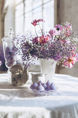 table set in lilac tones very peri color of the year 2022 with candle, statuette angel, purple marshmallow, butterfly and lilac gypsophila flowers, vintage decor in retro loft style room, celebration